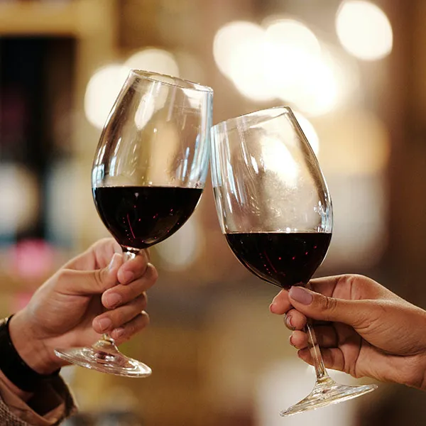 Τα χέρια κάνουν πρόποση σε ποτήρια κρασιού με κόκκινο κρασί